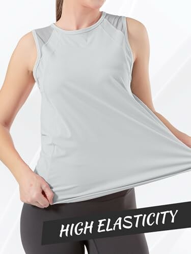 Mujer mostrando la elasticidad de una camiseta sin mangas gris.